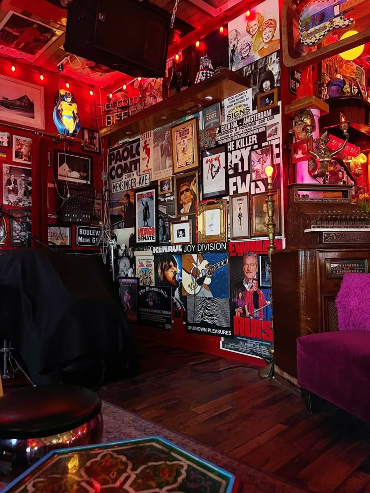 a room filled with lots of posters and lights on the wall next to a purple couch