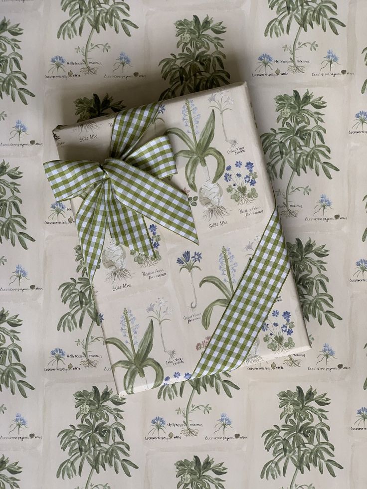 wrapping paper with green and white floral designs on it, tied up in a bow