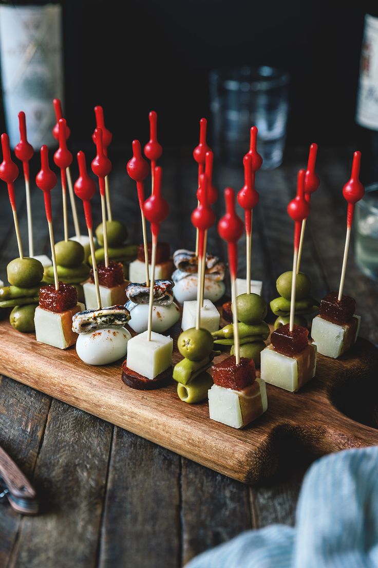 an assortment of appetizers are arranged on a cutting board with toothpicks