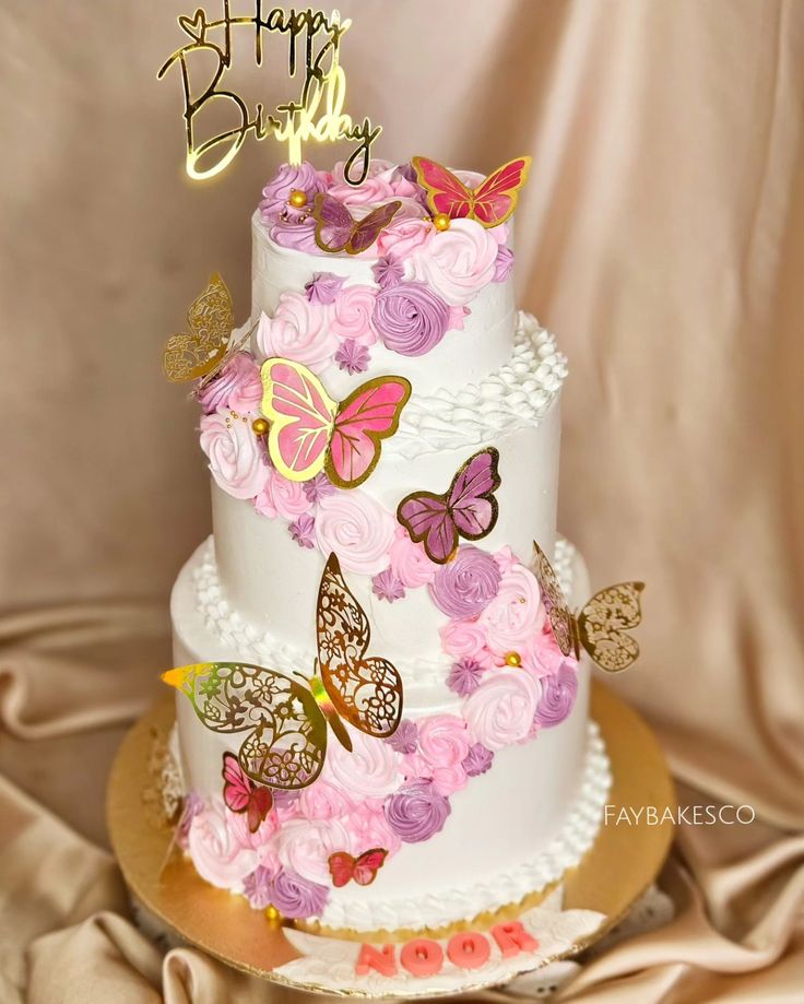 a three tiered cake decorated with pink and purple flowers, butterflies and the words happy birthday