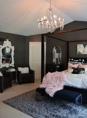 a bedroom with a four poster bed, chandelier and mirror on the wall