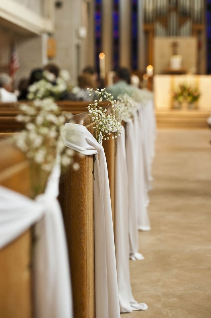 the pews are lined up with white cloth draped over them and baby's breath flowers