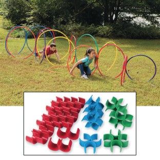 two children playing with different colored rings in the grass and one child sitting on the ground