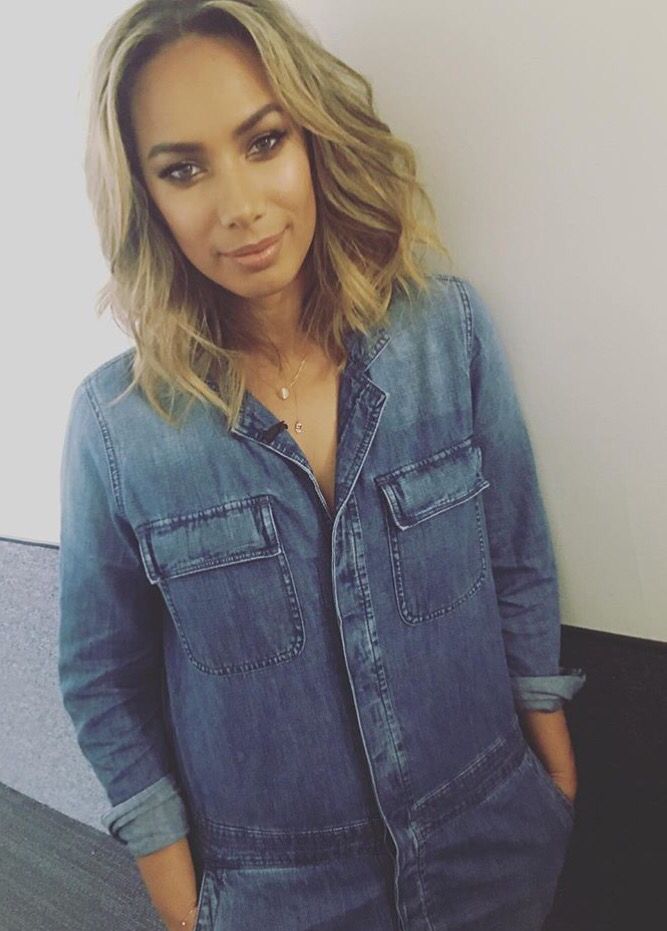 a woman standing in front of a wall with her hands on her hips and looking at the camera