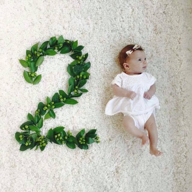 a baby is laying on the floor next to a number 2 made out of leaves