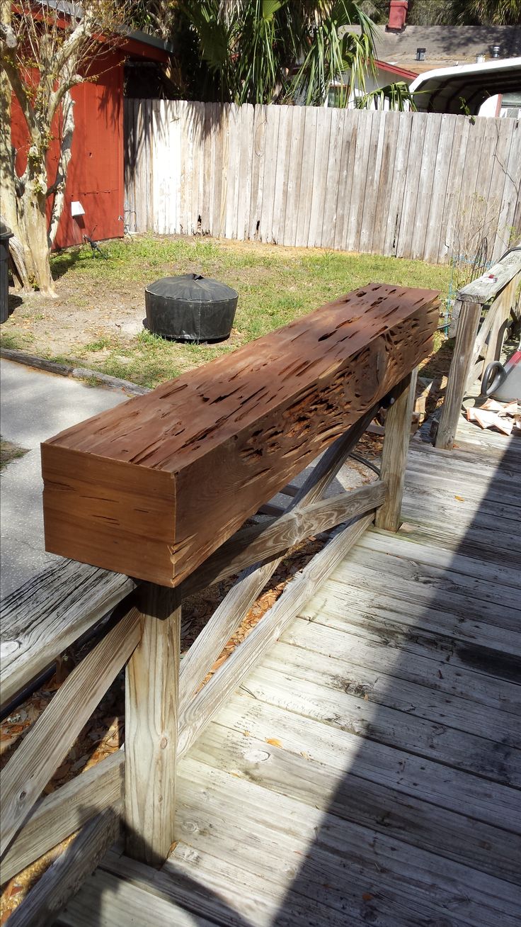 a wooden bench sitting on top of a wooden deck next to a yard and fence