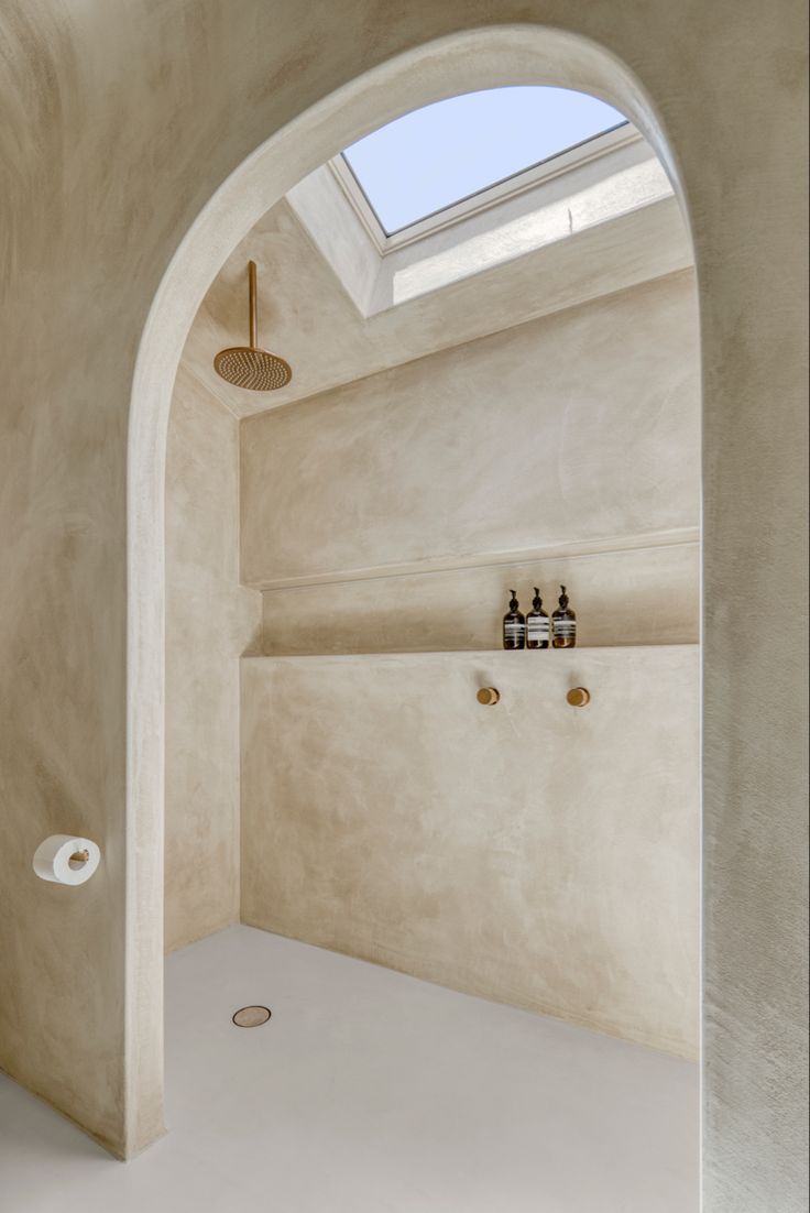 a bathroom with a skylight above the bathtub and toilet paper roll holders on the wall