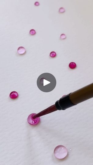 a close up of a pen with drops of water on the paper and pink confetti