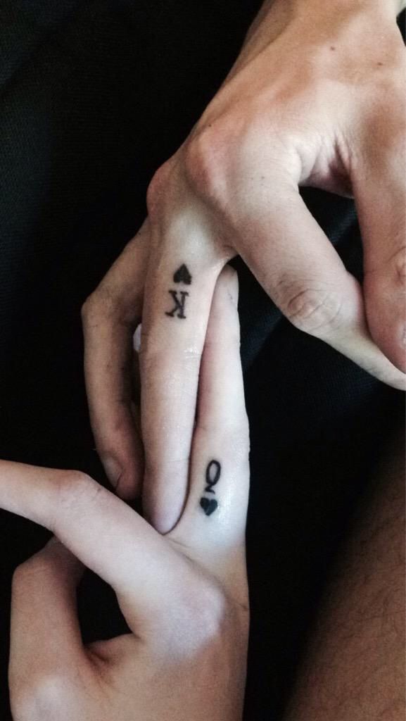 two people with matching tattoos on their fingers holding each other's hands and pointing to the opposite direction