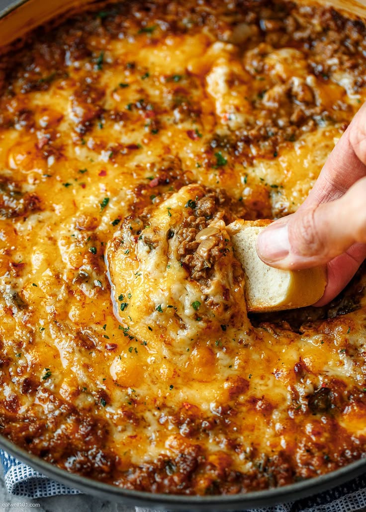 a hand is dipping cheese into a skillet