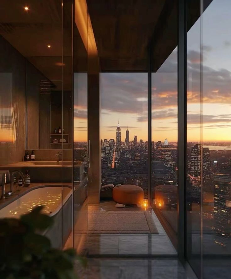 a bathroom with a large window overlooking the city at sunset or dawn, and a jacuzzi tub in the foreground