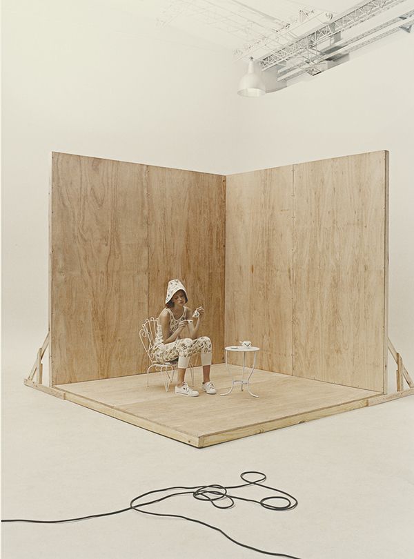 a woman sitting on a chair in front of a wooden paneled room with wires