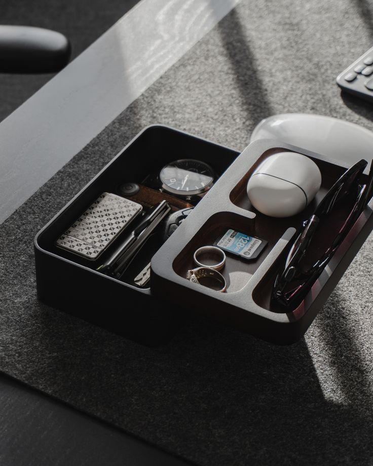 a desk with a keyboard, mouse and other office supplies in a black box on the table