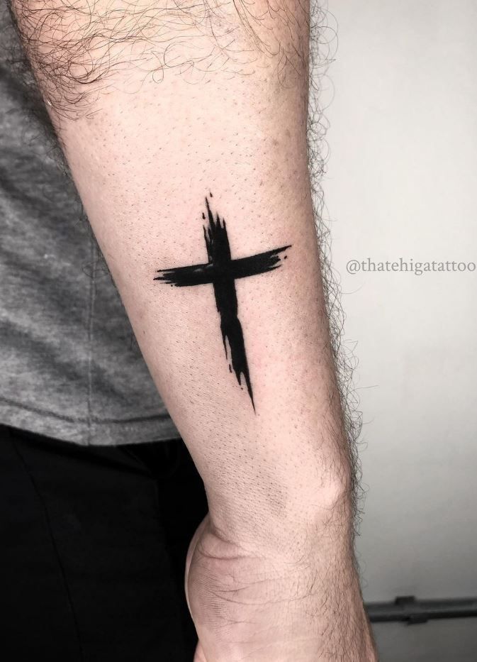 a man's arm with a black cross tattoo on the left side of his arm