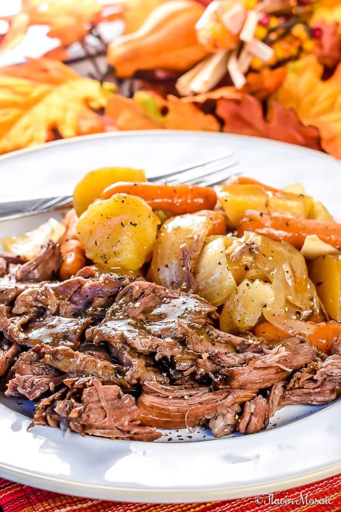 a white plate topped with roast, potatoes and carrots on top of a table