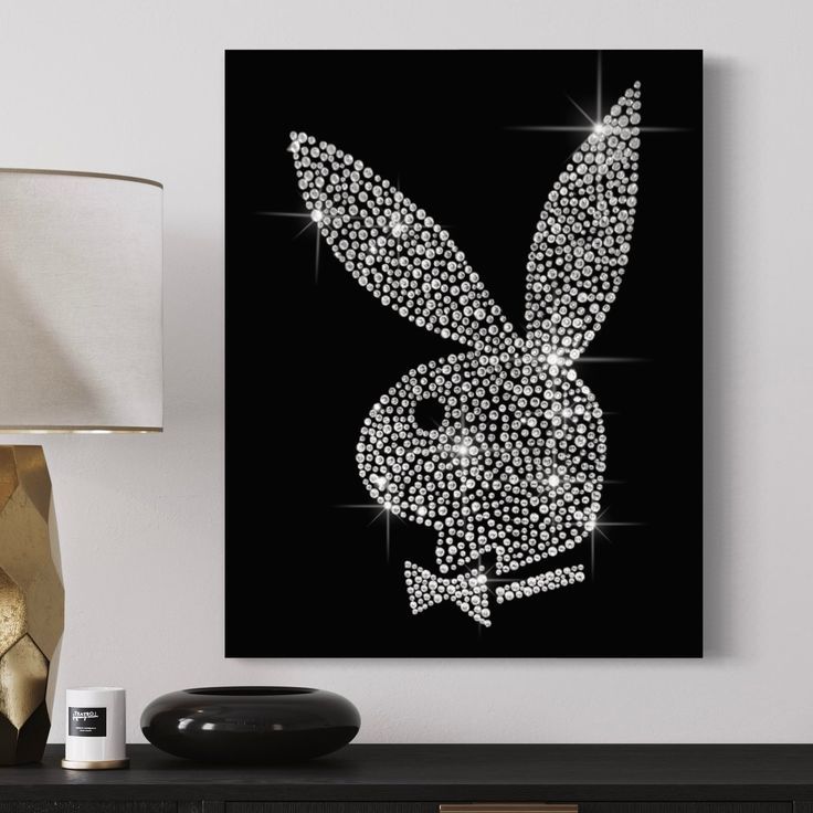 a black and white bunny rabbit art piece on a wall next to a table lamp