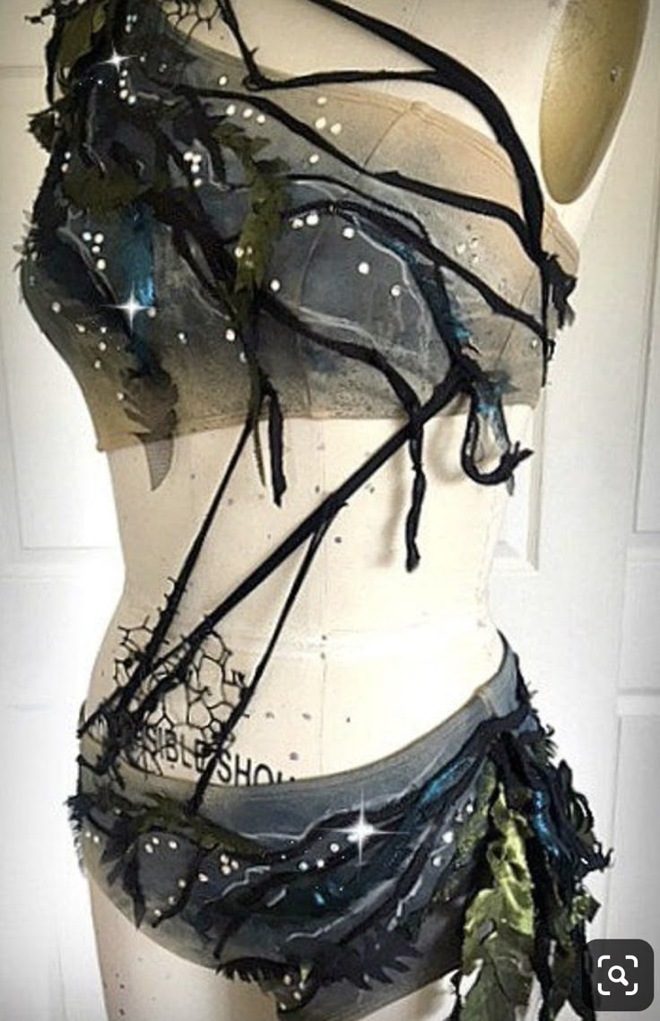 a mannequin is covered in black and silver fabric, with leaves on it