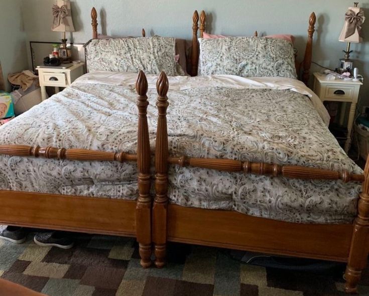 a bed with two wooden posts in a bedroom next to a dresser and lamp on the floor