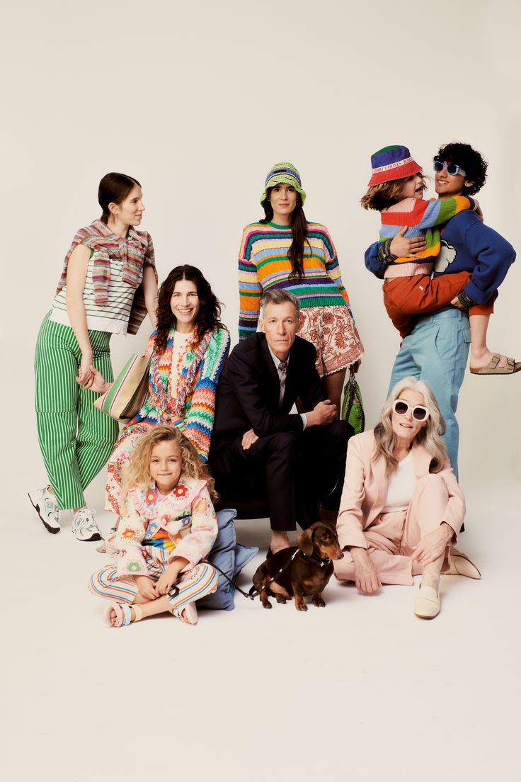 a group of people sitting next to each other in front of a white background with one person holding a dog