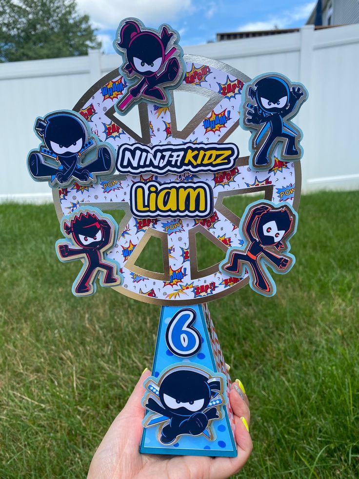 a person holding up a paper cut out of a clock with cartoon characters on it