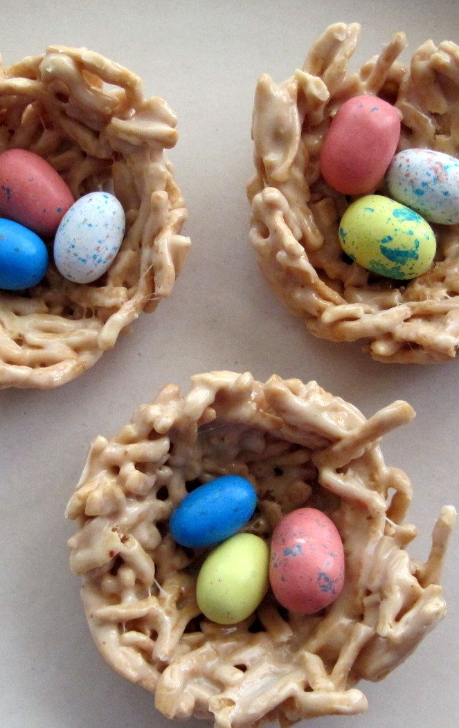 four small nests filled with candy eggs on top of a table