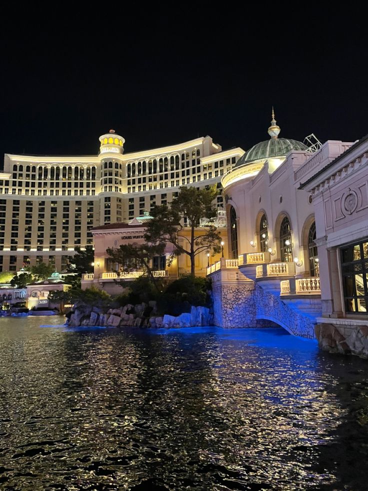 the las vegas hotel and casino is lit up at night with blue lights on the water