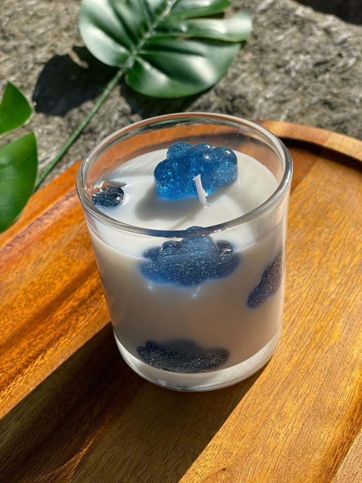 a candle that is sitting on top of a wooden table next to some plants and rocks