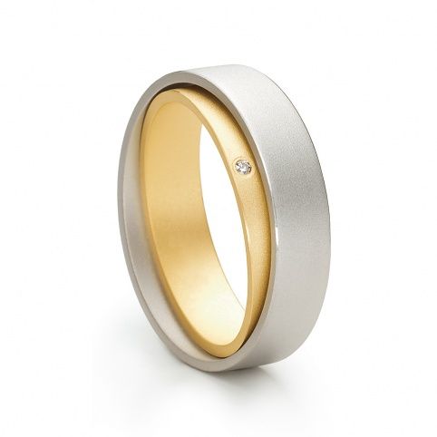 a white and yellow gold wedding ring with a diamond in the center, on a white background