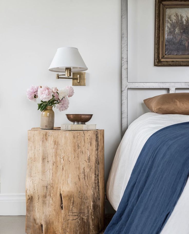 a bedroom with a bed, nightstand and flowers on the table in front of it