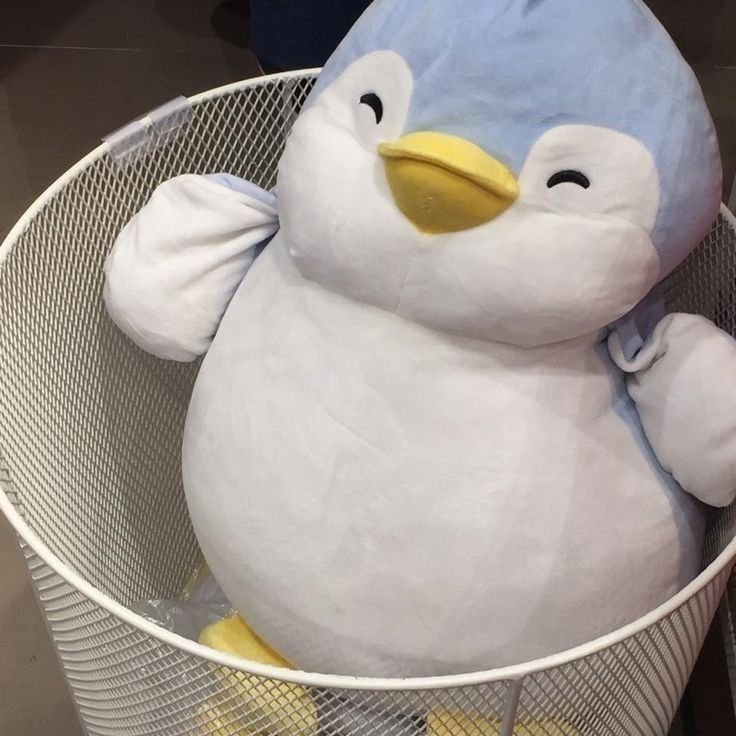 a stuffed penguin sitting in a wire basket