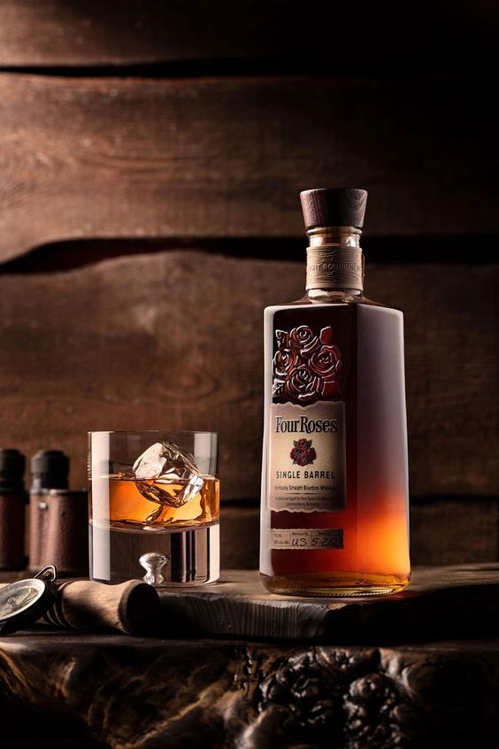 a bottle of whisky sitting on top of a wooden table next to other bottles and glasses