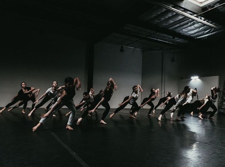 a group of people standing on top of a black floor in front of a white wall