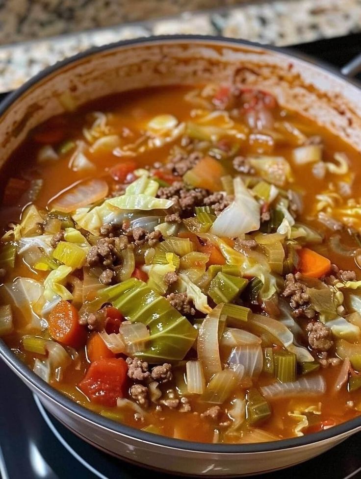 a bowl of soup on top of a stove with meat, vegetables and noodles in it