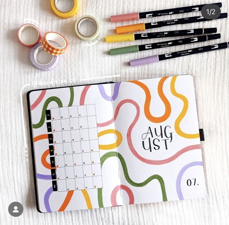 an open planner with markers, tape and washi tapes next to it on a table