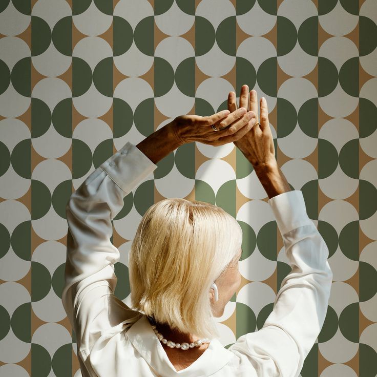 a woman standing in front of a wall with circles on it and her hands above her head