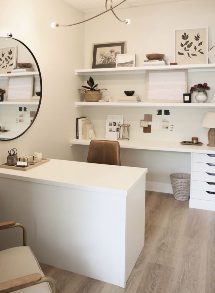 a white desk sitting under a round mirror in a room with lots of shelving