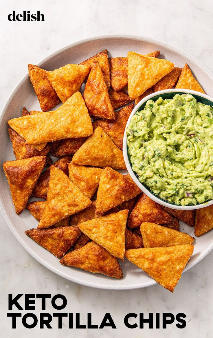 a white plate topped with tortilla chips and guacamole