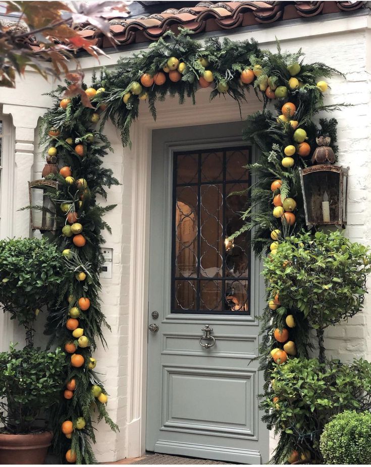 an orange garland on the front door of a house with potted plants around it