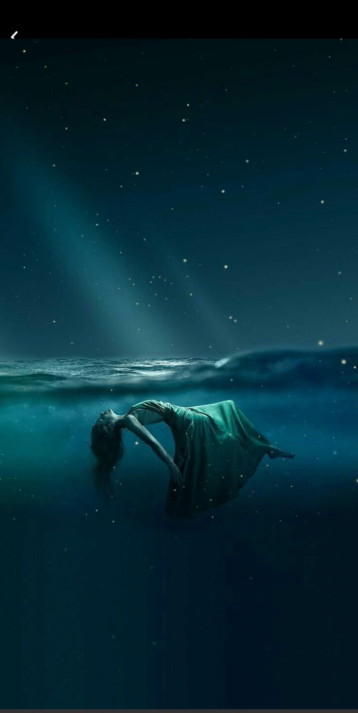 a woman is floating in the water at night