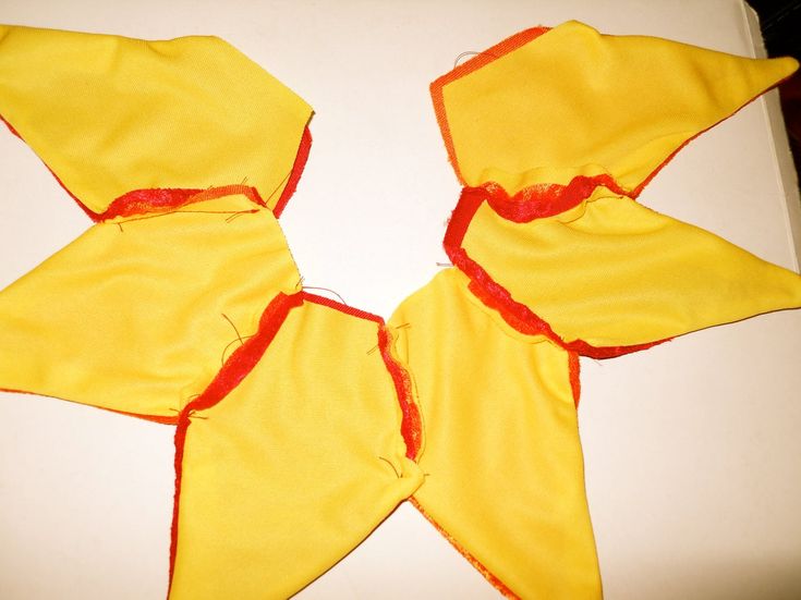 three pieces of yellow fabric with red thread on them sitting on top of a white surface