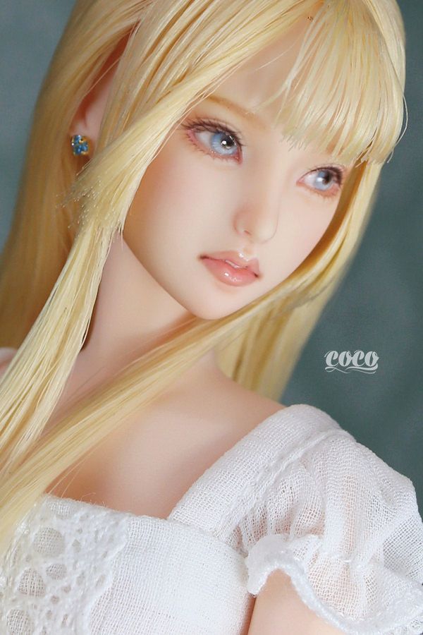 a doll with long blonde hair and blue eyes wearing a white dress is posing for the camera