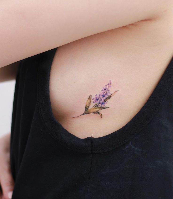 a woman's stomach with a small tattoo on it that has purple flowers growing out of it