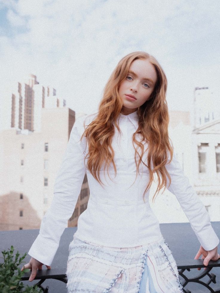 a woman with long red hair standing on a balcony