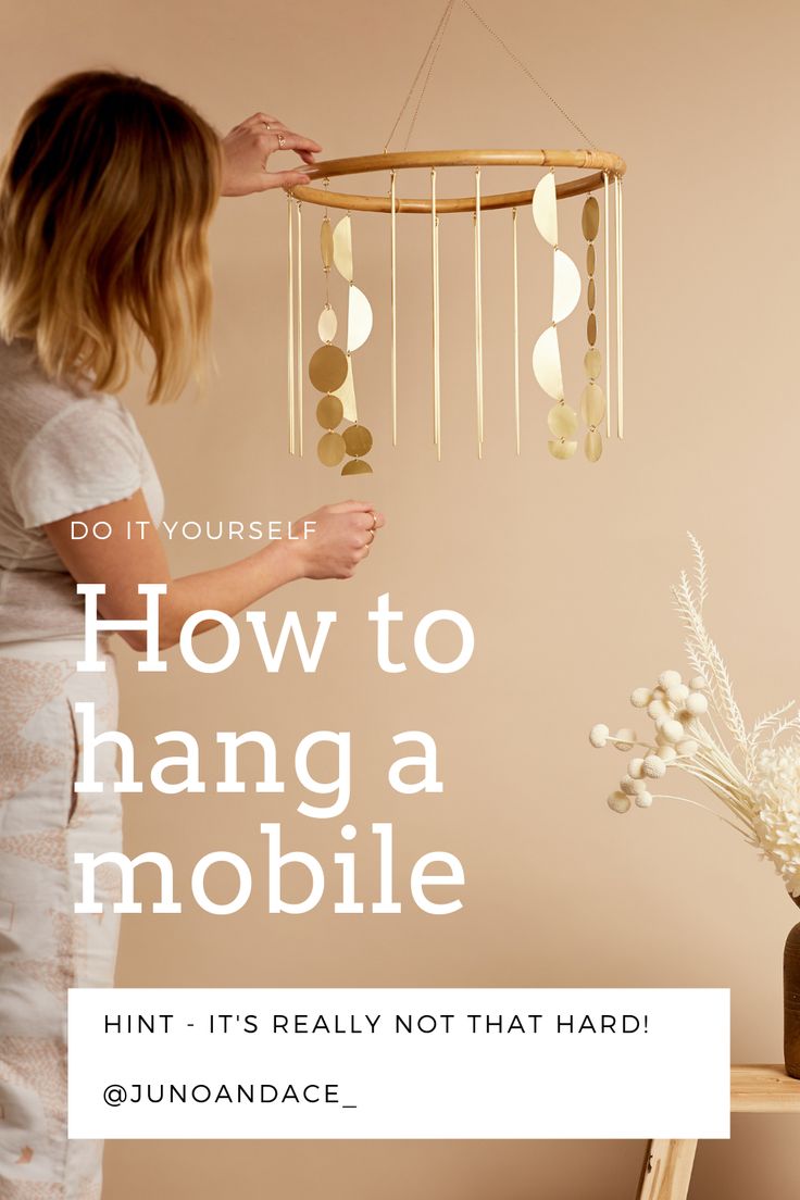 a woman standing next to a table with a mobile hanging from it's ceiling