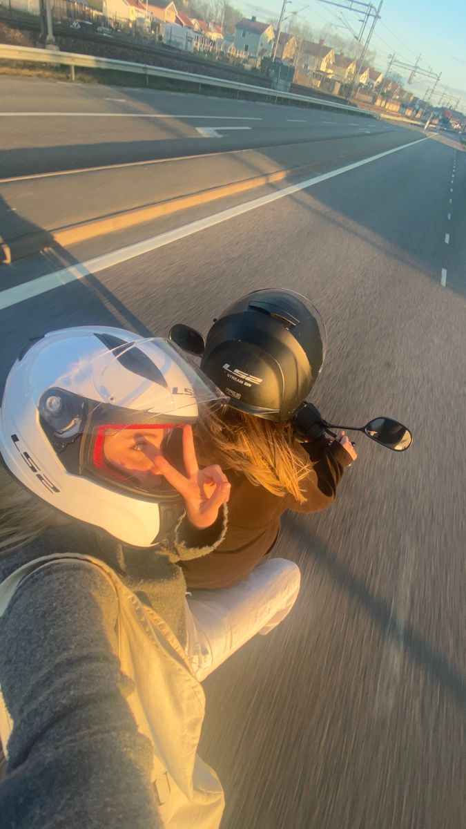 a person on a motor bike riding down the street in front of a camera man