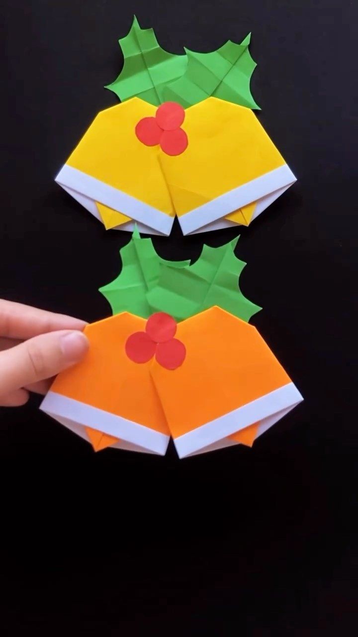 someone is holding an origami christmas tree with holly leaves on it and red berries on the top