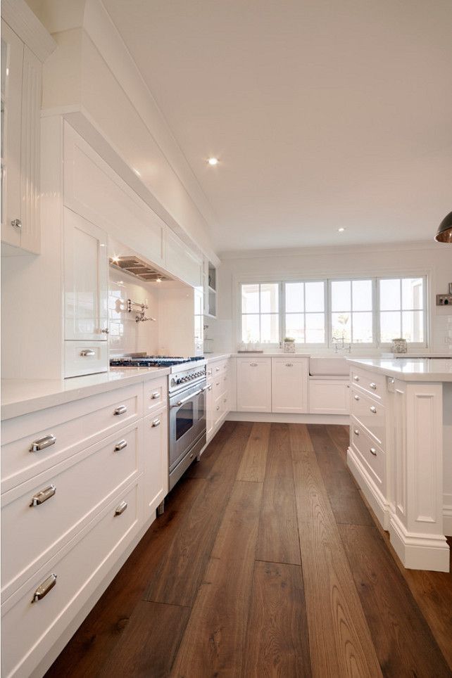 a large kitchen with white cabinets and wood flooring is seen in this image from the front view