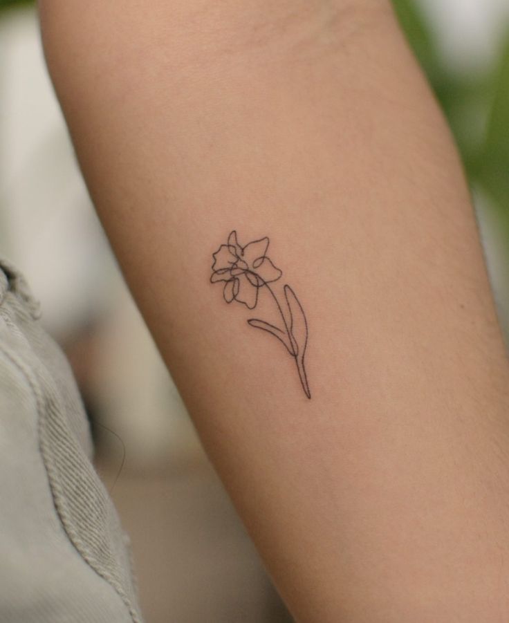 a woman's arm with a small flower tattoo on the left side of her arm