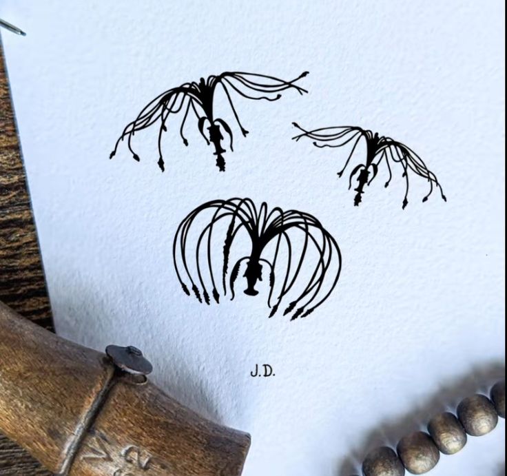 an ink drawing of three flowers on white paper next to a rubber stamp with the letter d