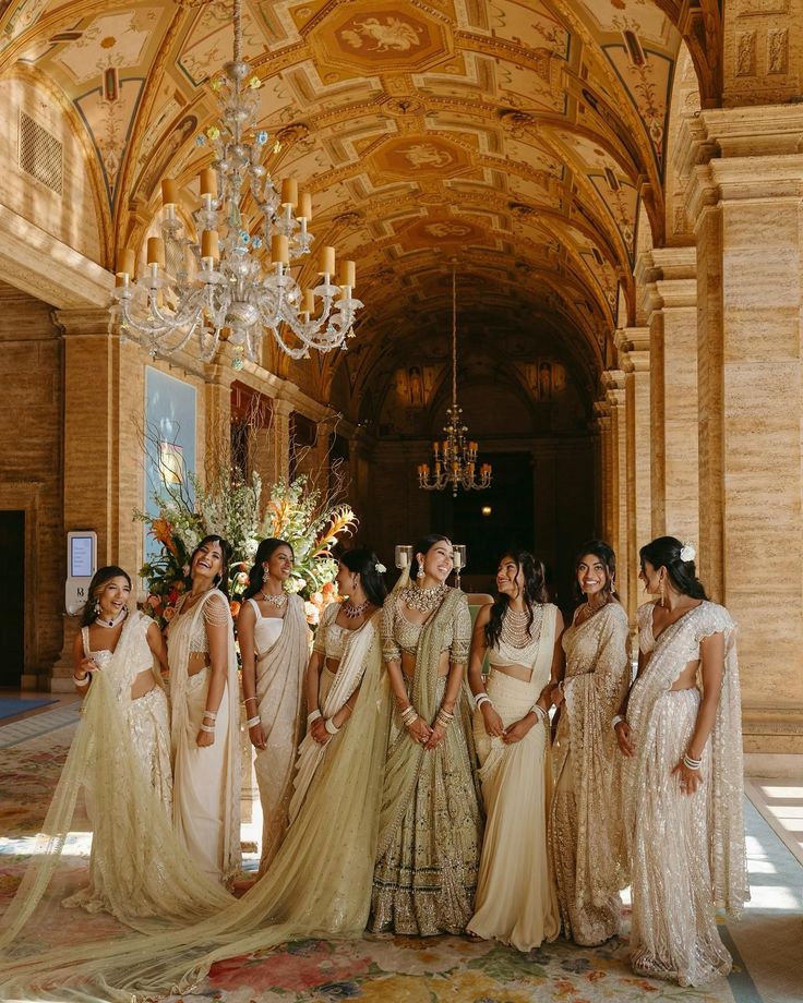 a group of women standing next to each other in front of a chandelier